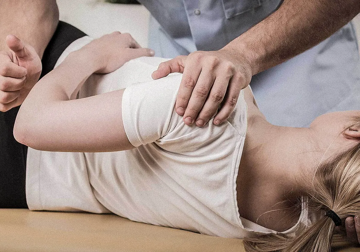 OMT-fysioterapeutti mobilisoi asiakkaan olkapäätä hoitopöydällä